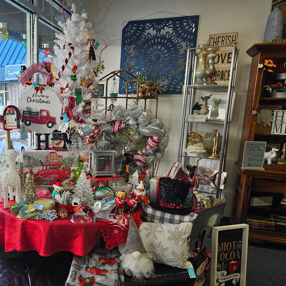 Decorative Christmas display with a white tree, ornaments, and festive decor in a store setting.