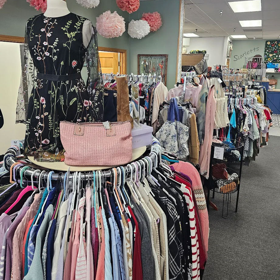Vintage clothing store with racks of clothes and a mannequin wearing a floral dress.