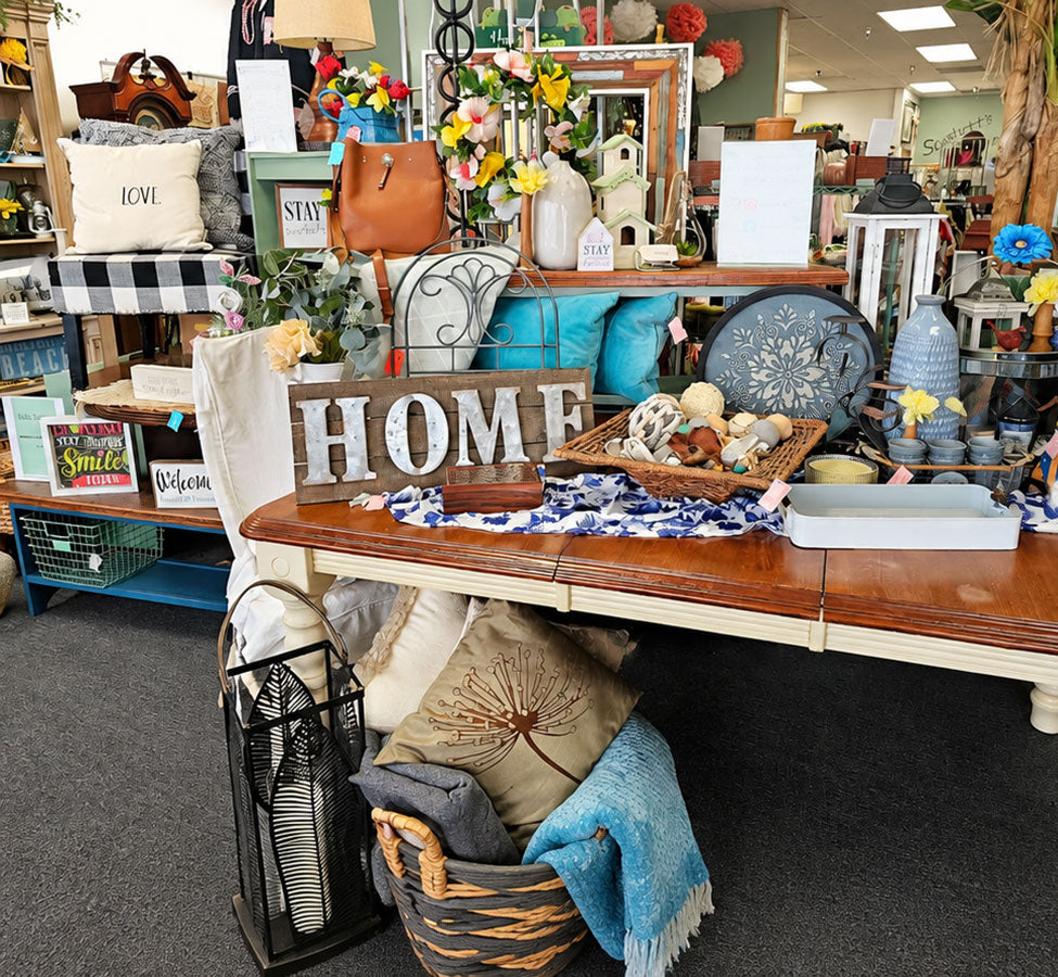 Decorative items on a table with 'HOME' sign in a store setting