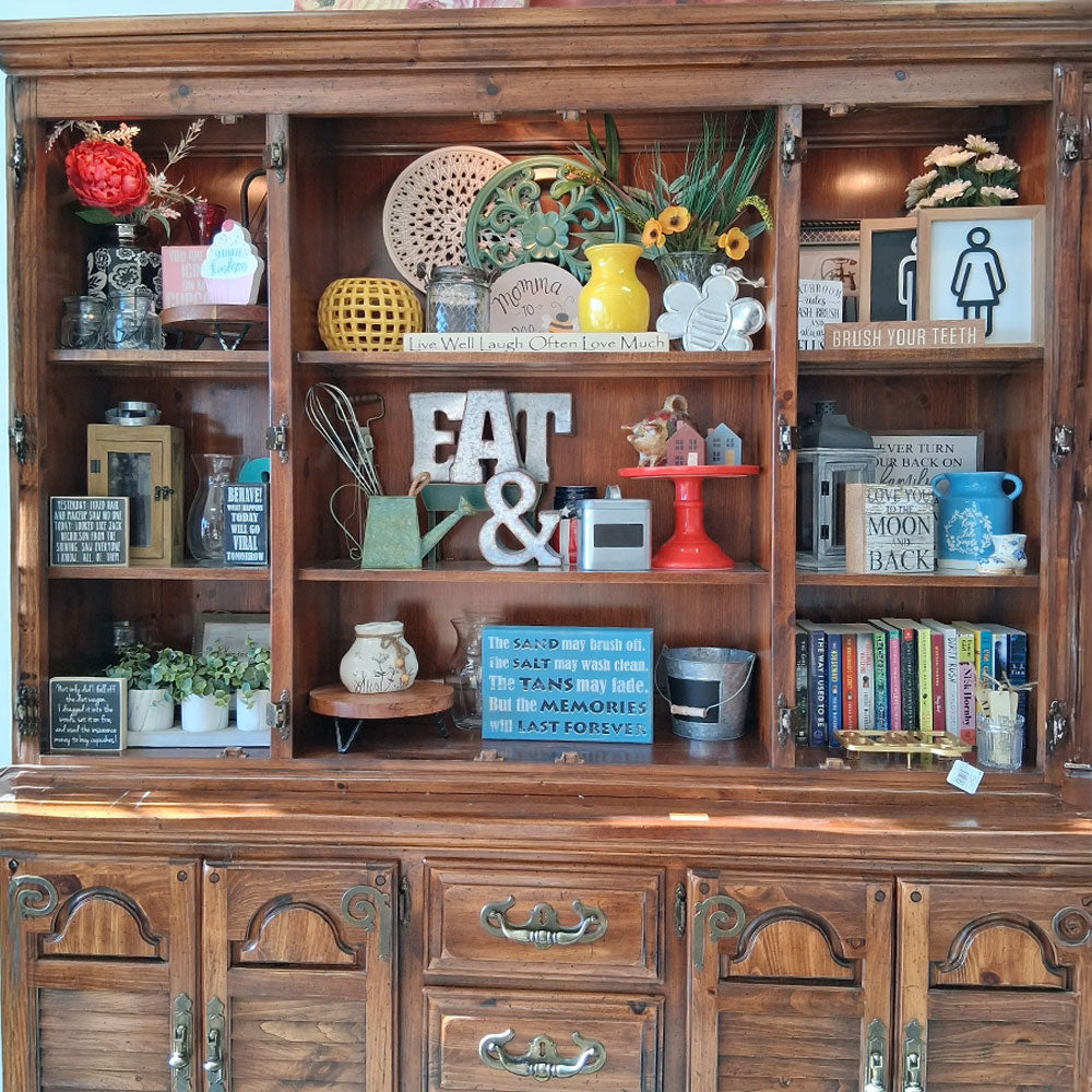 Wooden cabinet with decorative items including books, plants, and a 'Eat &' sign.